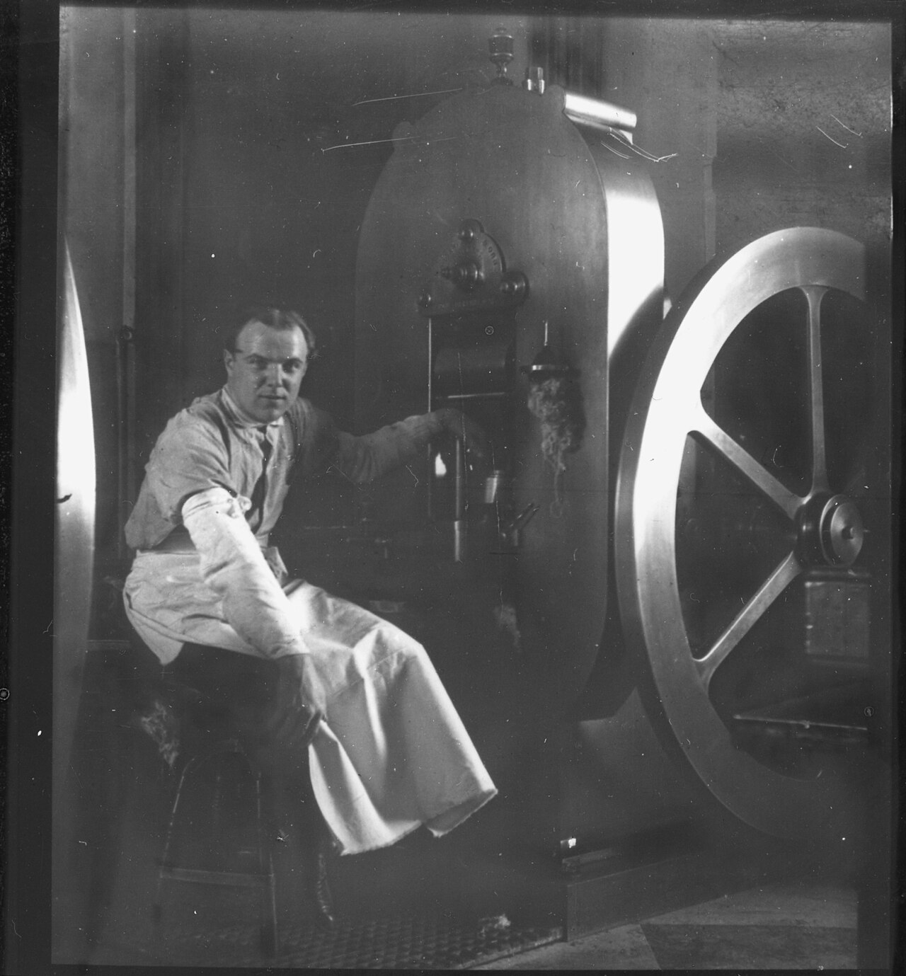 A U.S. Mint press operator seated beside a coining press