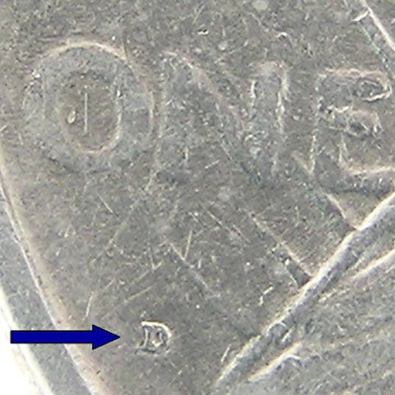 Close-up of a Peace dollar reverse with an arrow pointing to the small D mintmark below ONE